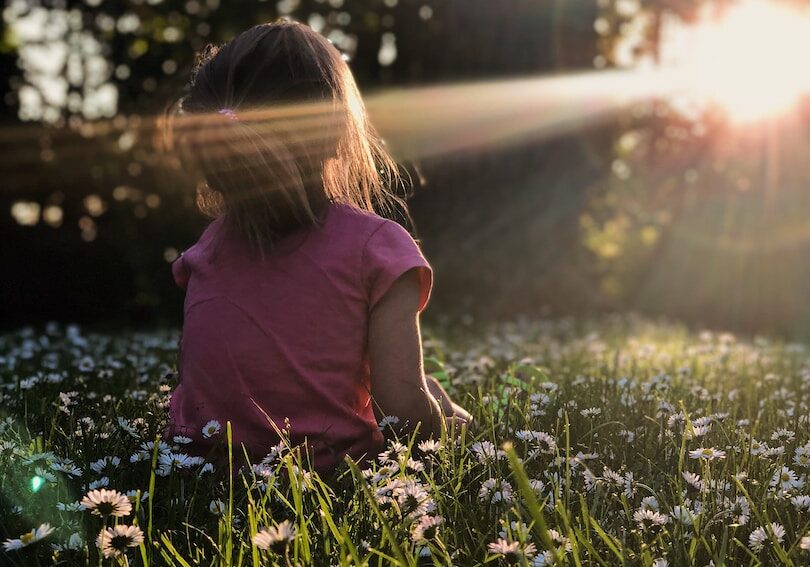 Photo by Melissa Askew girl sitting on daisy flowerbed in forest